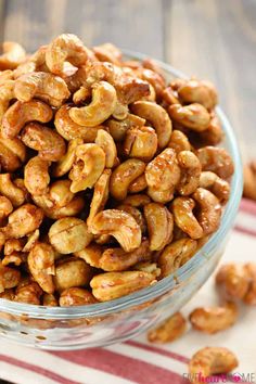 a glass bowl filled with cashews sitting on top of a table next to a red and white striped napkin