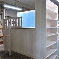 an unfinished book shelf in the middle of a room with other bookshelves and furniture