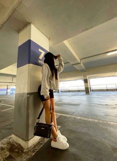 a woman leaning against a wall with her hand on her head and purse in front of her