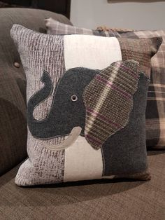 two pillows with an elephant on them sitting on a couch