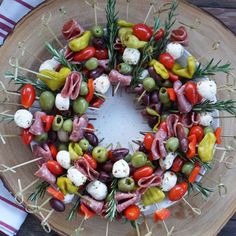 a wreath made out of various vegetables on a wooden platter with napkins and utensils