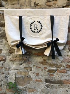 a towel hanging on the side of a stone wall with black ribbon and monogrammed initials