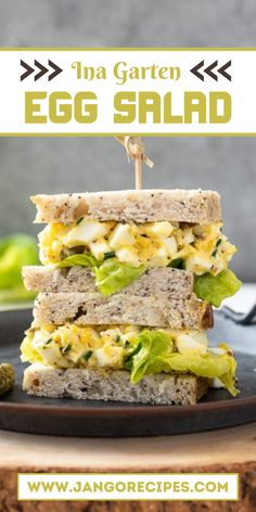 an egg salad sandwich with lettuce and tomato on it is stacked up on a black plate