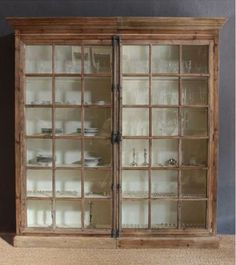 an old wooden cabinet with glass doors on the top and bottom, against a gray wall