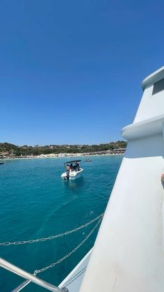 two people on a boat in the middle of the ocean with another boat behind them