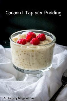 a glass bowl filled with pudding and raspberries on top of a white cloth