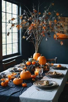 a dining room table is set with pumpkins and other fall decorations, including an artificial tree