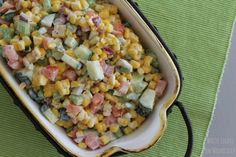 a bowl filled with corn and cucumbers on top of a green tablecloth