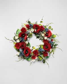 a wreath with red flowers and greenery on the front is displayed against a white background