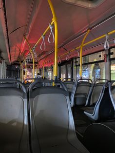 the interior of a public transit bus with empty seats and yellow handles on each side