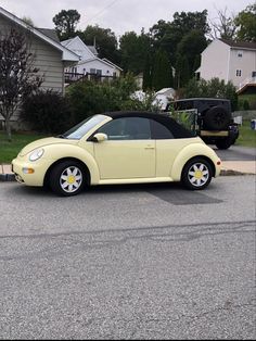 a small yellow car parked in a parking lot next to a house and yard area