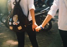 two people holding hands while standing next to each other in front of motor scooters