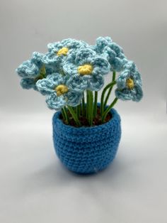 small crocheted blue pot with flowers in it