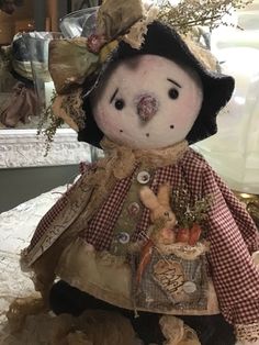 a stuffed animal is dressed up like a scarecrow and holding a basket full of pumpkins