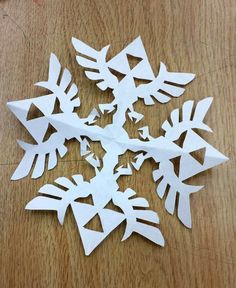 cut out paper snowflakes sitting on top of a wooden table