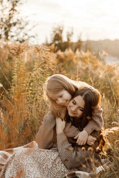 two girls are hugging in the tall grass