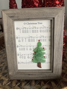 a christmas tree made out of sheet music is displayed in a frame on a table