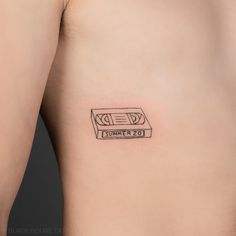 a small tattoo on the back of a man's left side stomach that has a tape recorder printed on it