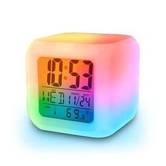 the alarm clock is multicolored and has been placed on top of a white surface