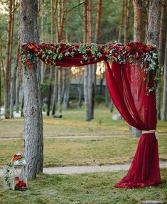 an outdoor wedding setup with red drapes and greenery