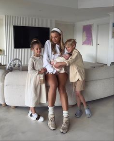 two women and three children standing in front of a couch with a baby on it