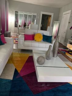 a living room filled with white furniture and colorful rugs