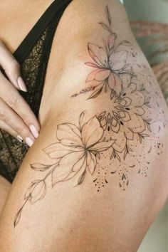 a close up of a woman's thigh with tattoos on it and flowers in the middle