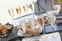 several glasses of champagne are sitting on a table with bread and crackers in front of them