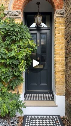 a black and white checkered door mat in front of a brick building with an arched doorway