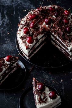 a chocolate cake with cherries on top and two slices missing from the cake plate