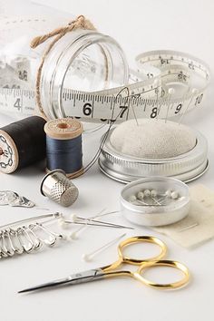 sewing supplies including scissors, thread, measuring tape and spools on a white surface