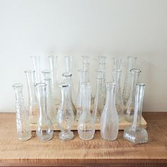 a wooden table topped with lots of glass vases