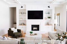 a living room with white furniture and a flat screen tv