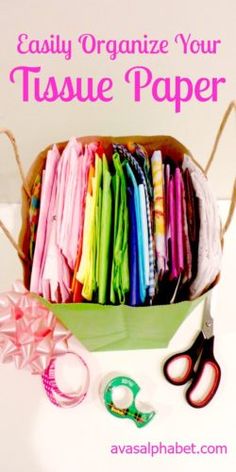 a box filled with lots of different colored clothes next to scissors and ribbon on the table