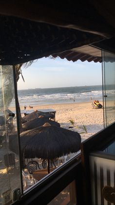 the beach is lined with thatched umbrellas and people are in the water behind them