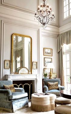 a living room filled with furniture and a chandelier hanging from the ceiling over a fire place