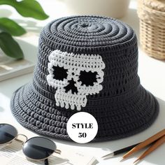 a crocheted skull hat sitting on top of a table next to some sunglasses