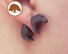 two tiny rhinoceros are sitting next to each other on a persons side ear