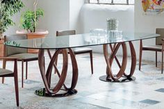 a glass table with chairs around it and a potted plant in the corner next to it