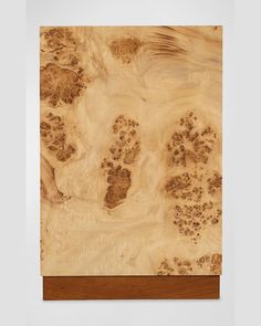 an abstract wooden artwork piece with brown and white designs on the wood, including paw prints