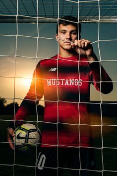 a man holding a soccer ball in front of a net