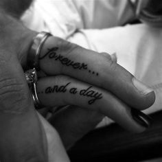 two people holding hands with tattoos on their fingers that says forever and a day written in cursive writing