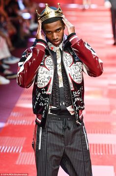 a man with a crown on his head walks down the runway