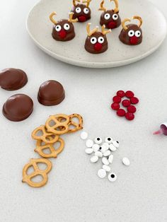 chocolate covered pretzels, candy eyes and candies on a white plate next to other food items