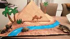 a desert scene made out of paper with animals and a camel on the ground next to a river