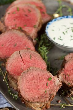 sliced steak on a platter with ranch dip in the middle and herbs sprinkled on top