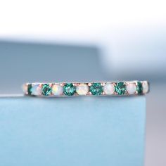 a close up view of a wedding band with green and white stones on the side