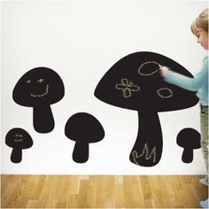 a child is drawing on the wall with black chalk and white paint, which looks like mushrooms