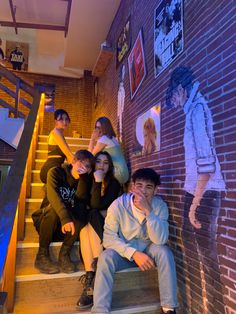 a group of young people sitting on the steps in front of a brick wall and stairs