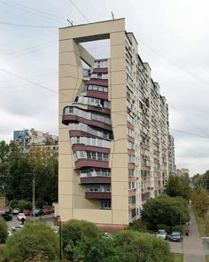 a tall building with balconies on the side and windows in the top floor